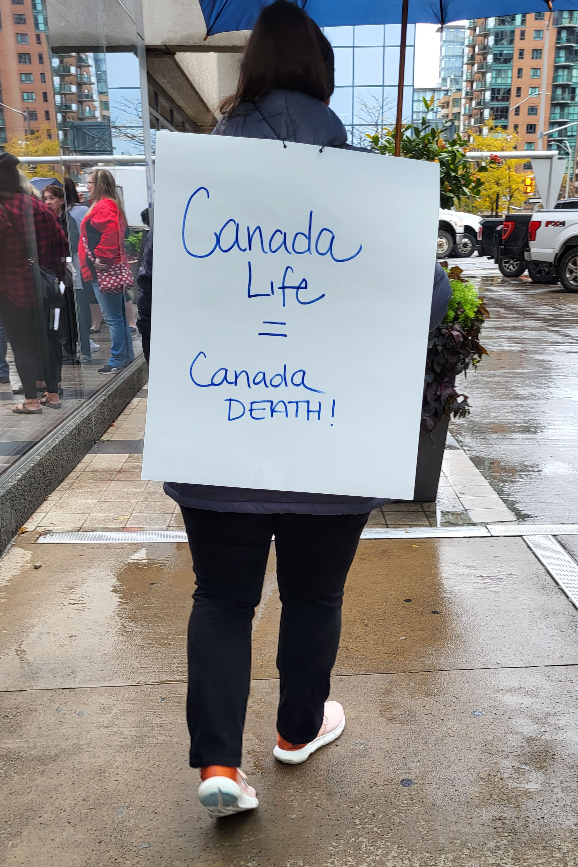 member holding sign Canada Life = Canada Death