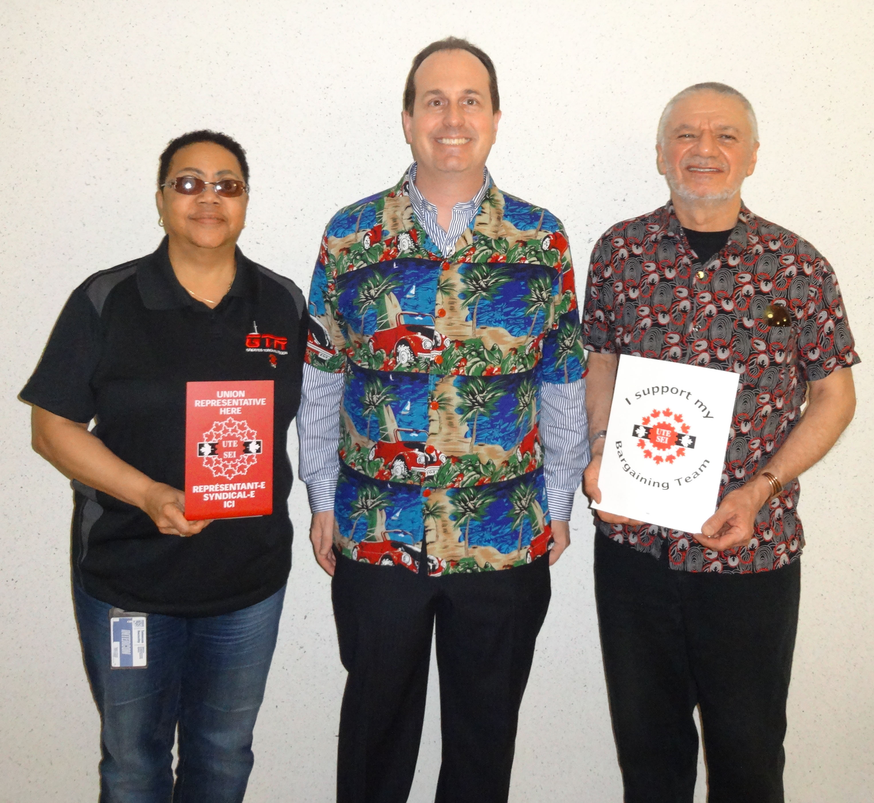 Ryan Ward, Mani Mifsud et Vona Martin posant avec les panneaux SEI et habillés dans les couleurs du syndicat et des couleurs vives pour notre journée de "Célébration"