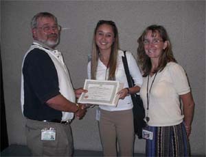  Natalia Korczynski receiving her UTE scholarship from Brother Bob Magee while her mother Grace Korczynski looks on.